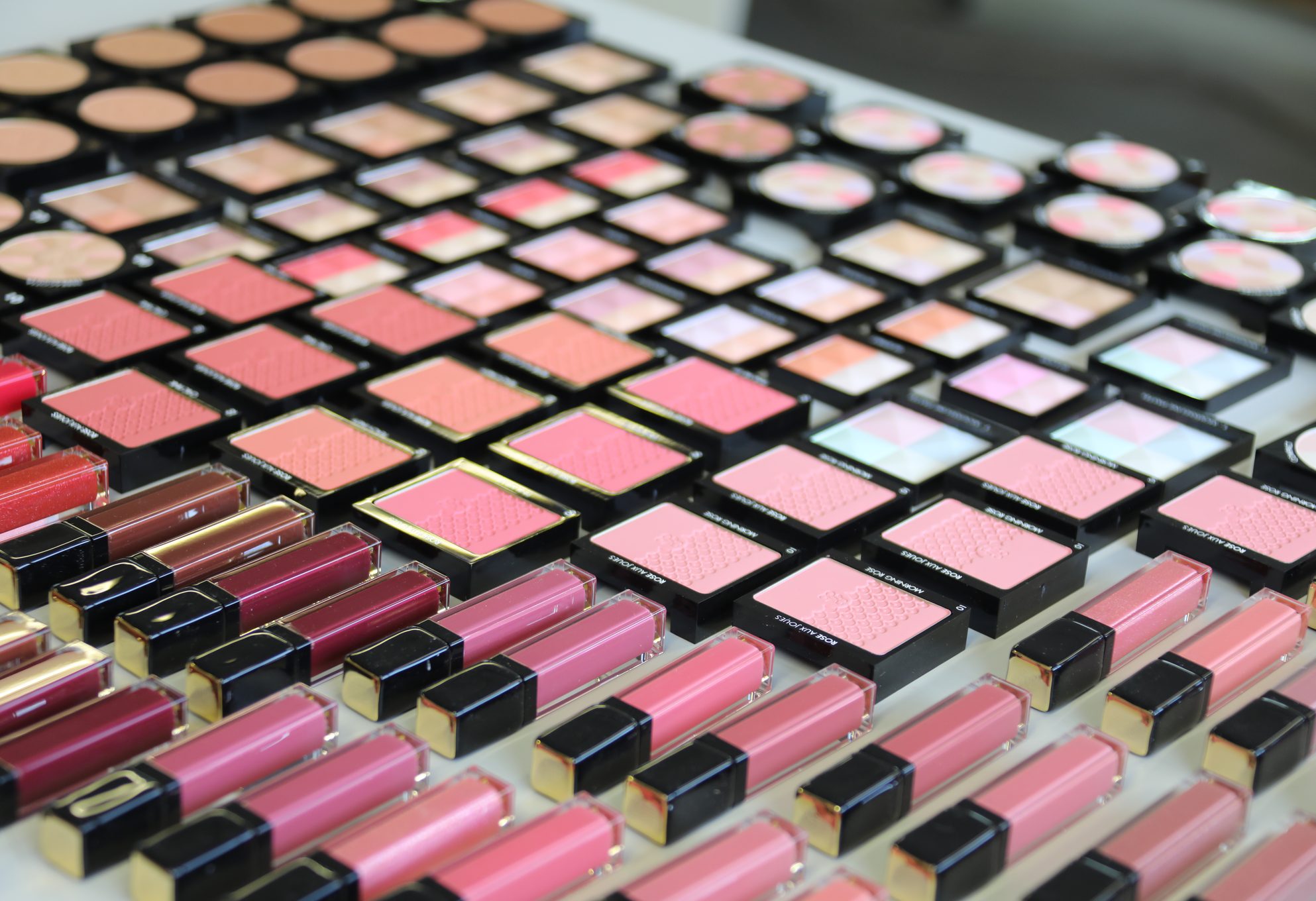 Fards à joues et gloss disposés sur un linéaire de maquillage
